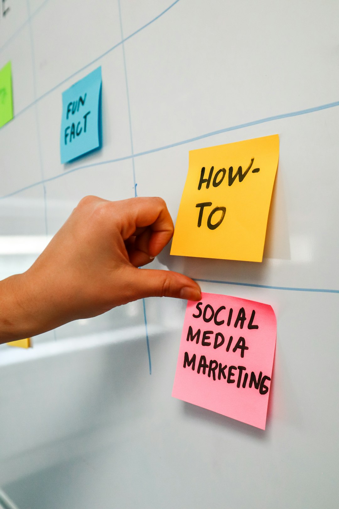 services-03 Person sticking a post-it on a white board with the words Social Media Marketing written on it